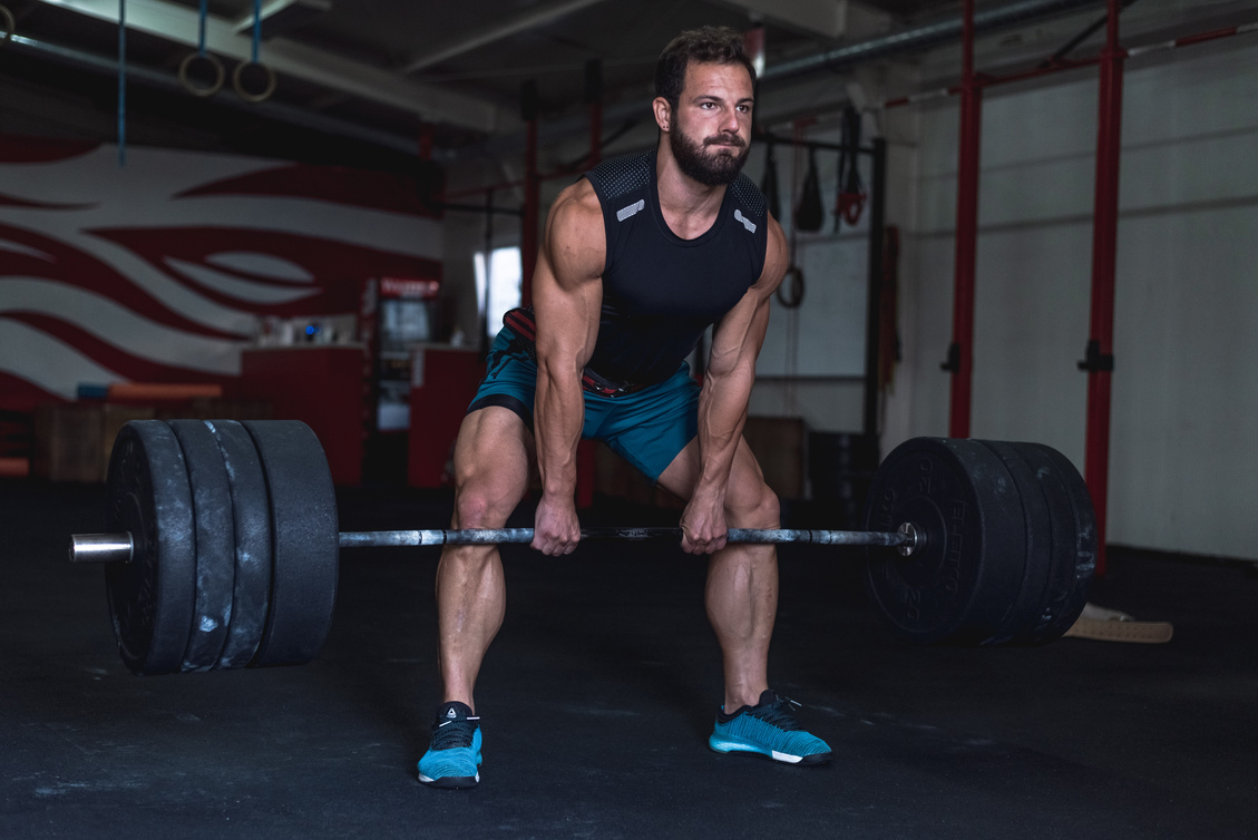 Man in Blue Tank Top Carrying a Barbell